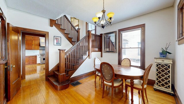 dining room with visible vents, light wood-type flooring, stairs, and an inviting chandelier