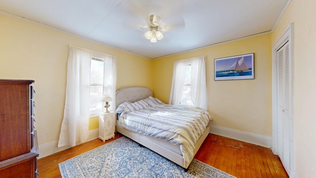 bedroom featuring a ceiling fan, wood finished floors, baseboards, and a closet