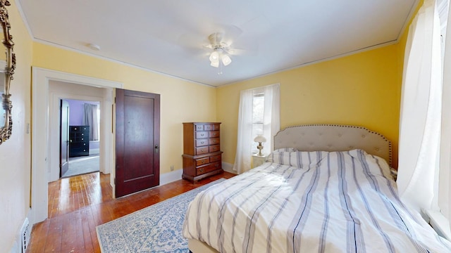 bedroom with ceiling fan, crown molding, baseboards, and hardwood / wood-style floors