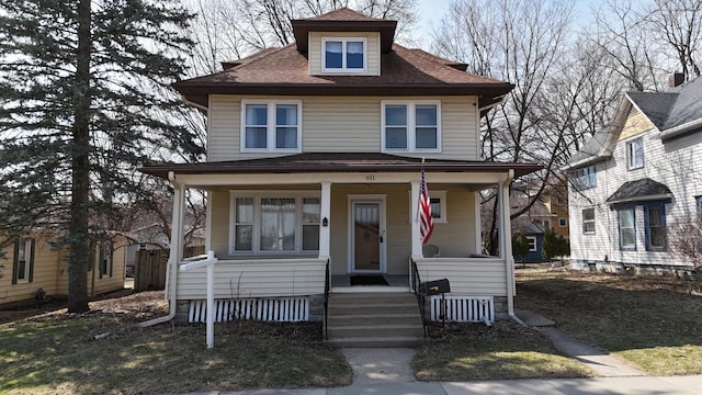 american foursquare style home with a porch and a shingled roof