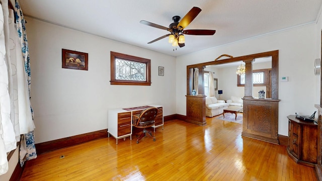 office featuring crown molding, baseboards, a ceiling fan, and light wood-style floors