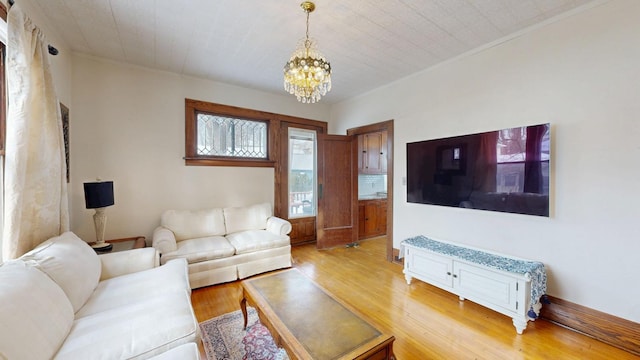 living area with ornamental molding, light wood-type flooring, and a notable chandelier