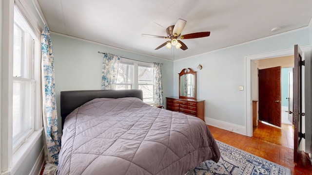 bedroom featuring ornamental molding, wood-type flooring, ceiling fan, and baseboards