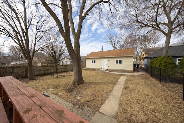rear view of property with an outdoor fire pit, a fenced backyard, and an outdoor structure