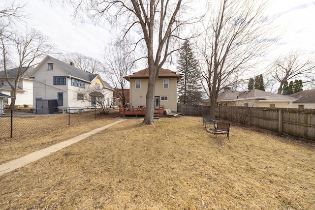 view of yard featuring a deck, a fenced backyard, and an outdoor fire pit