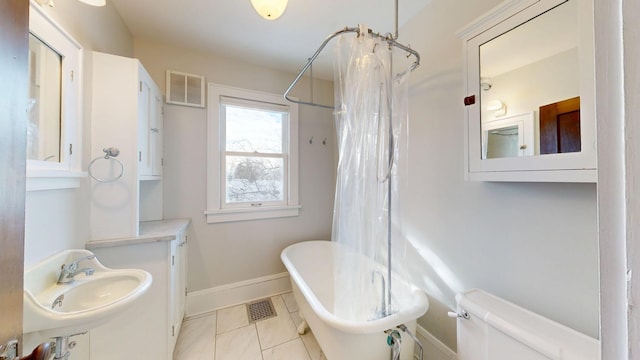 611 5th Ave SW, Rochester, MN 55902 - bathroom with a freestanding tub, baseboards, a sink, toilet, and a shower with curtain