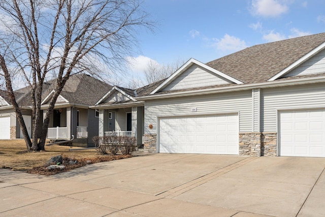 view of front of house featuring a garage, stone siding, a porch, and driveway