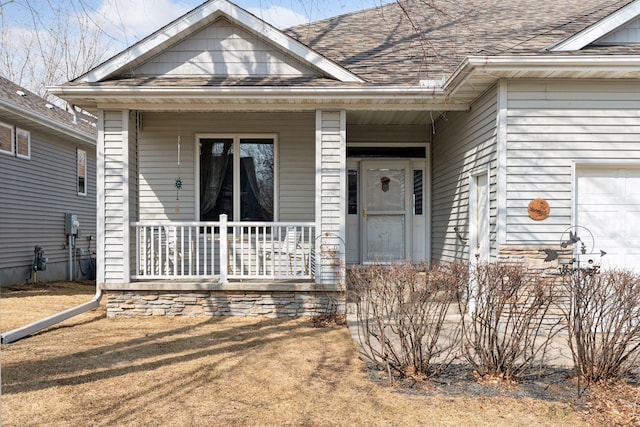 property entrance featuring a porch, an attached garage, and roof with shingles