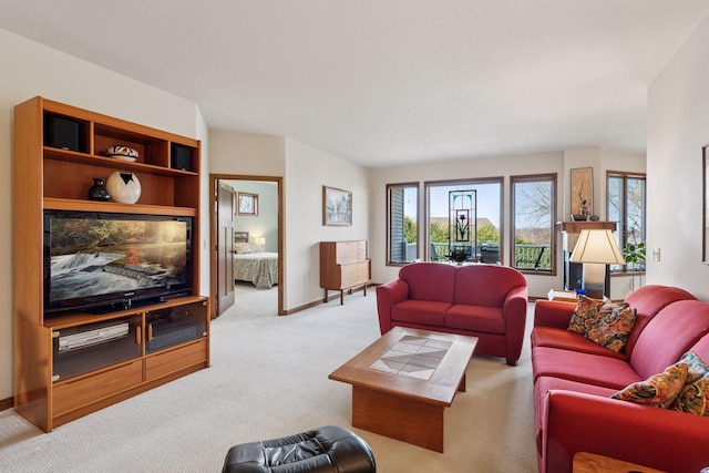 living area with a healthy amount of sunlight, baseboards, and light carpet