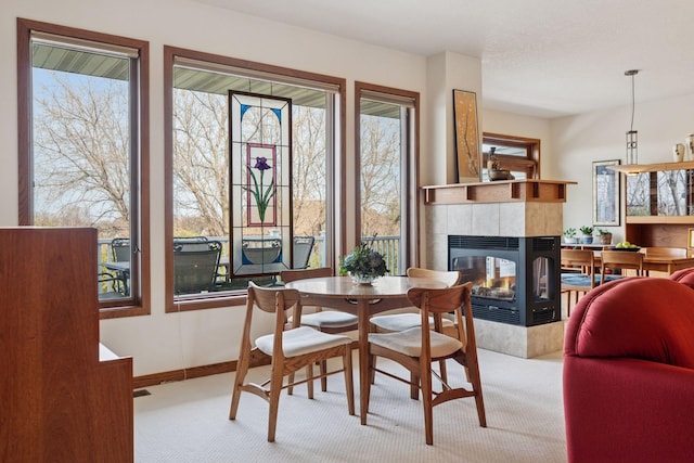 carpeted dining space featuring a tiled fireplace and baseboards