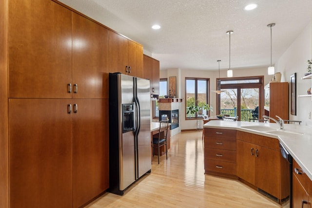 kitchen with a sink, stainless steel fridge, brown cabinets, and a tile fireplace