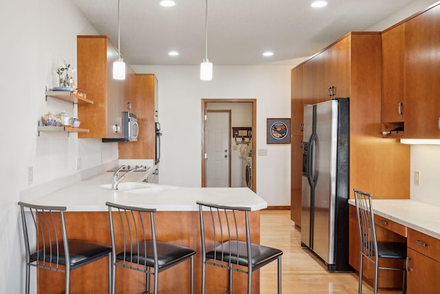 kitchen featuring a sink, brown cabinets, light wood-style floors, stainless steel appliances, and open shelves