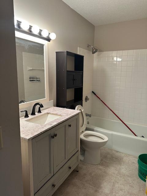 bathroom featuring vanity, a textured ceiling, bathing tub / shower combination, and toilet