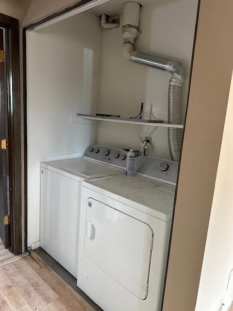 clothes washing area featuring laundry area, separate washer and dryer, and light wood-style floors