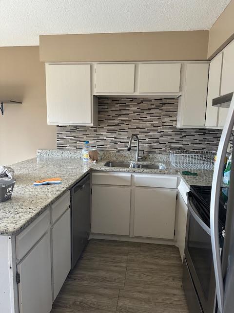 kitchen featuring dishwashing machine, a peninsula, electric range oven, decorative backsplash, and a sink