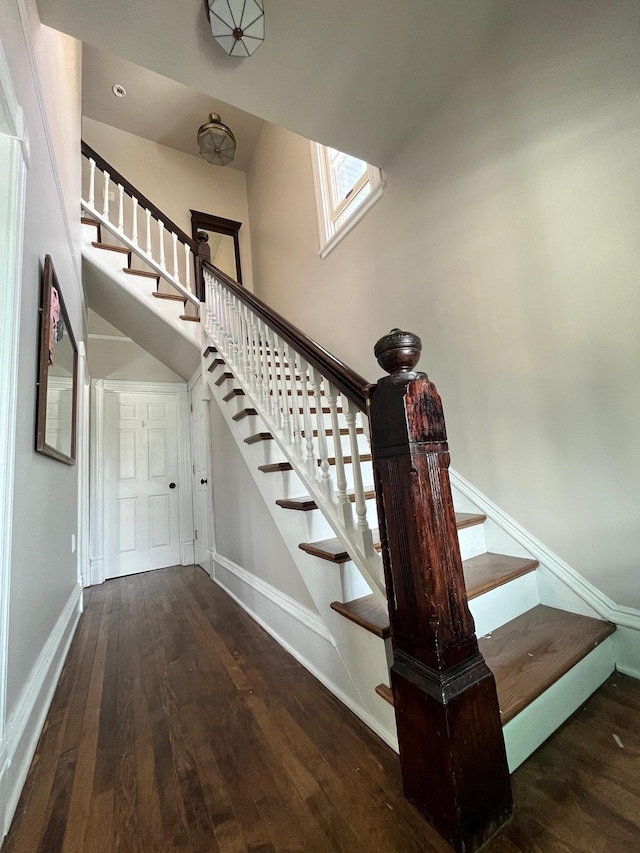 stairs with a high ceiling, wood finished floors, and baseboards