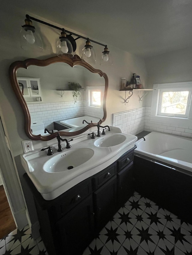 full bathroom featuring a wealth of natural light, a bath, and a sink