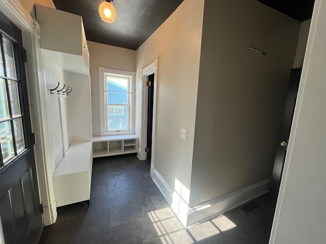 hall with stone tile flooring and baseboards