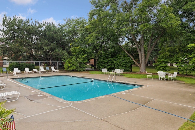 pool with a patio and fence