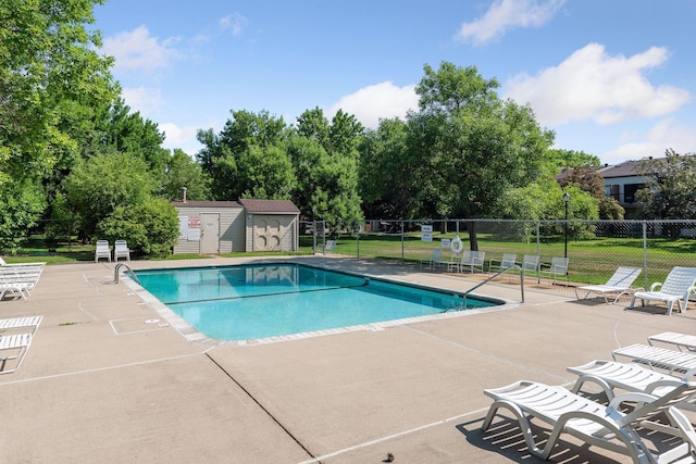 pool with a patio area, a lawn, an outdoor structure, and fence