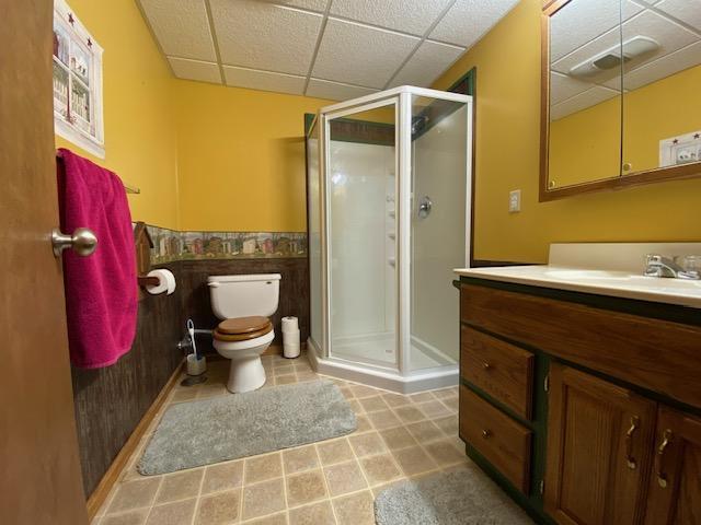 full bathroom with a drop ceiling, toilet, a stall shower, and vanity