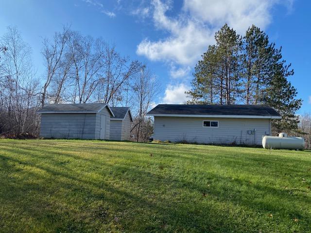 back of property with an outbuilding, a storage unit, and a yard