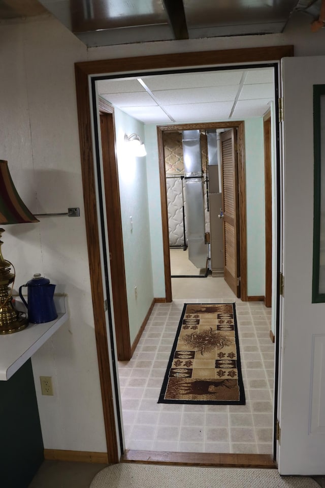 hall featuring baseboards and a drop ceiling