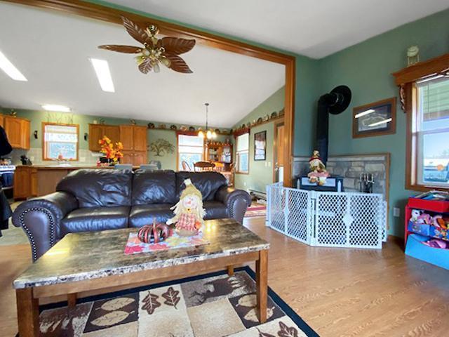 living room featuring a wealth of natural light, ceiling fan, a wood stove, and vaulted ceiling