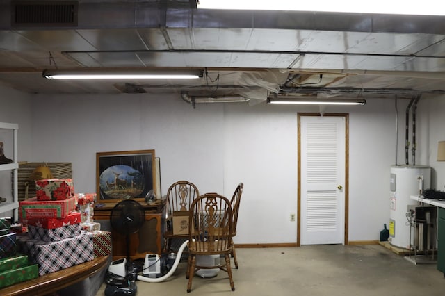 finished basement with water heater, visible vents, and baseboards