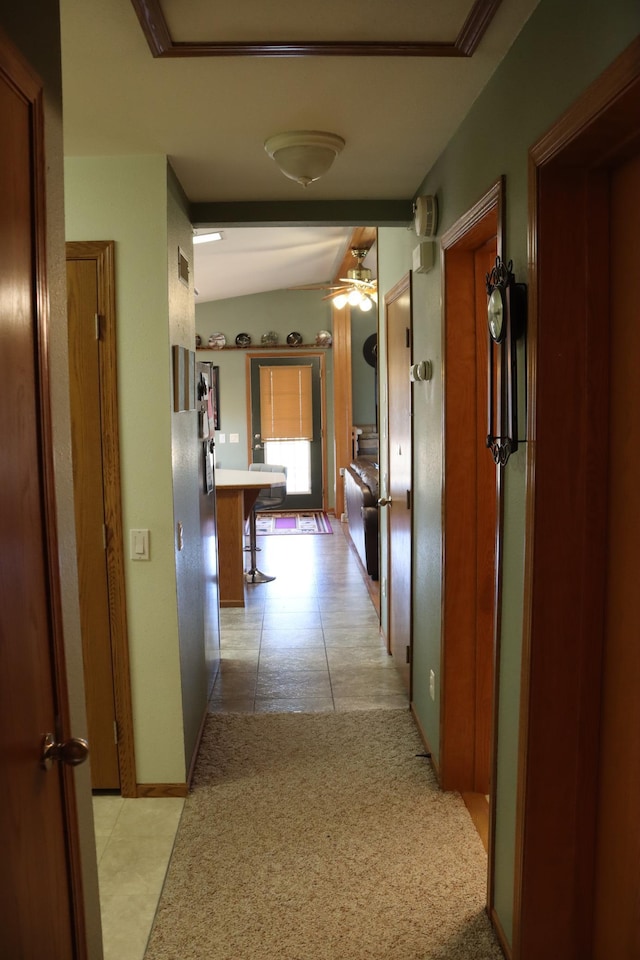 hall with light tile patterned floors, baseboards, light carpet, and vaulted ceiling