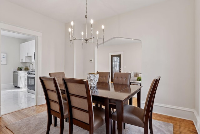 dining room featuring light wood-style flooring, baseboards, and a chandelier