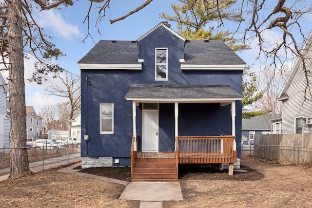 view of front of home featuring fence, roof with shingles, and stucco siding