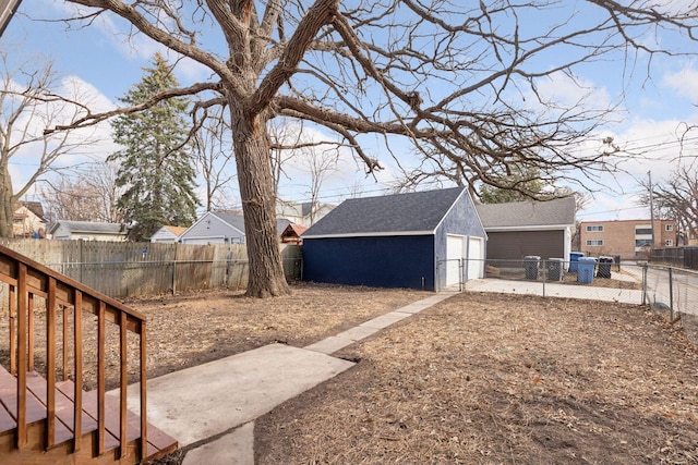 view of yard with a garage, an outbuilding, and a fenced backyard