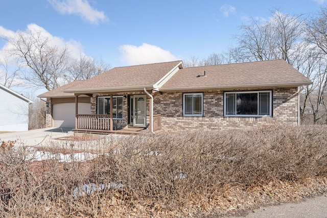 ranch-style home with a porch, concrete driveway, a shingled roof, a garage, and brick siding