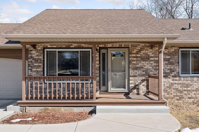 property entrance with a porch, a garage, brick siding, and a shingled roof