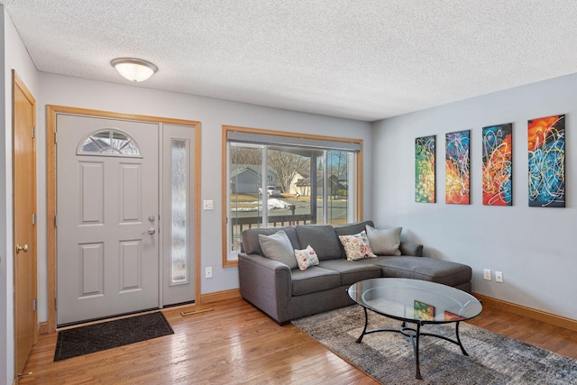 living room featuring a textured ceiling, baseboards, and wood finished floors