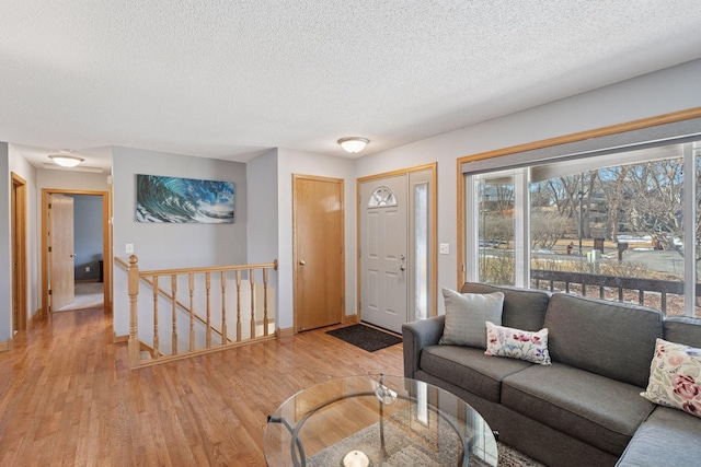 living area with light wood-type flooring, baseboards, and a textured ceiling