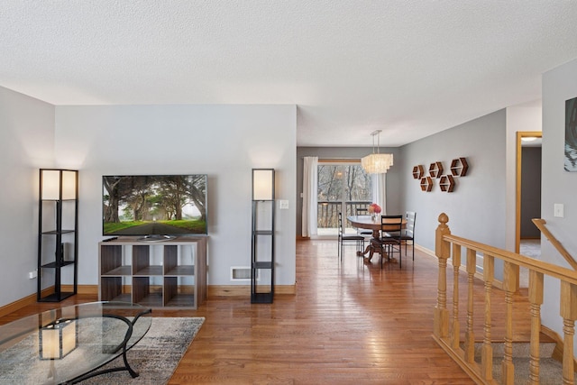 living area with baseboards, a textured ceiling, and wood finished floors