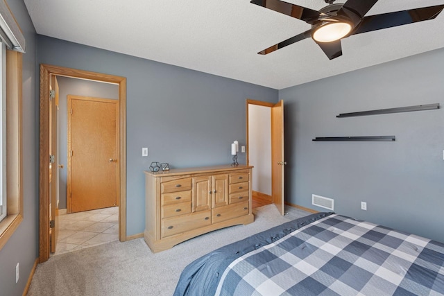 bedroom with visible vents, light colored carpet, baseboards, and ceiling fan