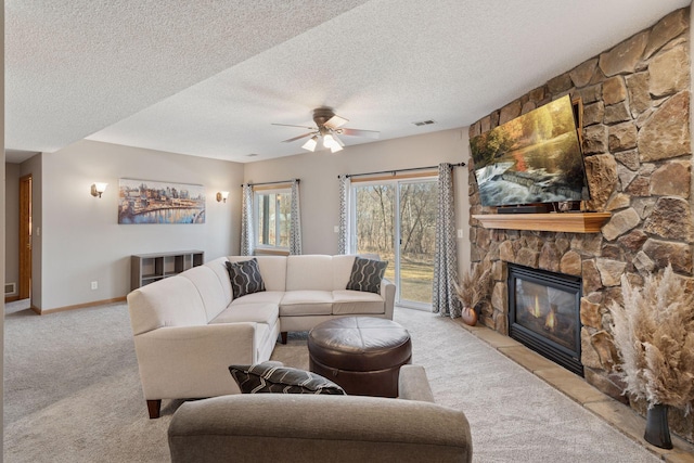 living area featuring baseboards, visible vents, carpet floors, a fireplace, and ceiling fan