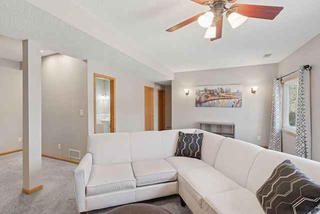 carpeted living area featuring visible vents, baseboards, a textured ceiling, and ceiling fan