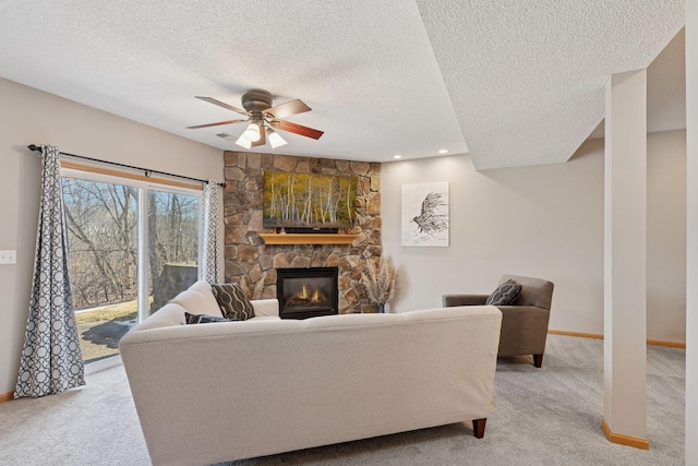 living room featuring light carpet, a fireplace, baseboards, and ceiling fan