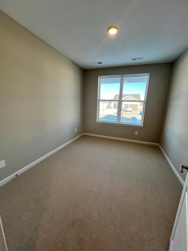 empty room with carpet, baseboards, and visible vents