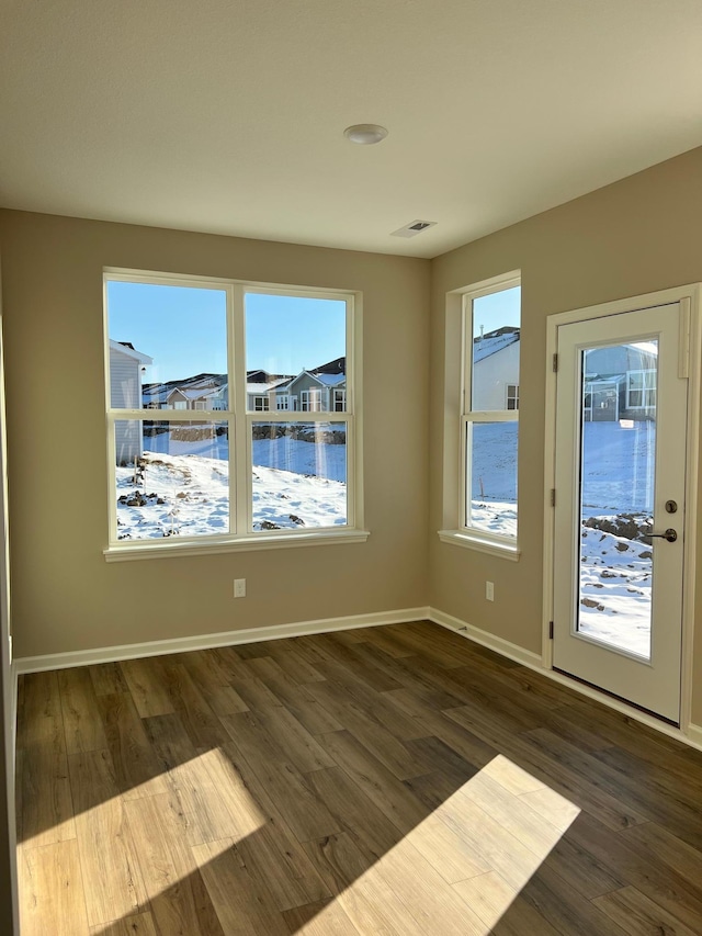 unfurnished room featuring visible vents, baseboards, and dark wood finished floors