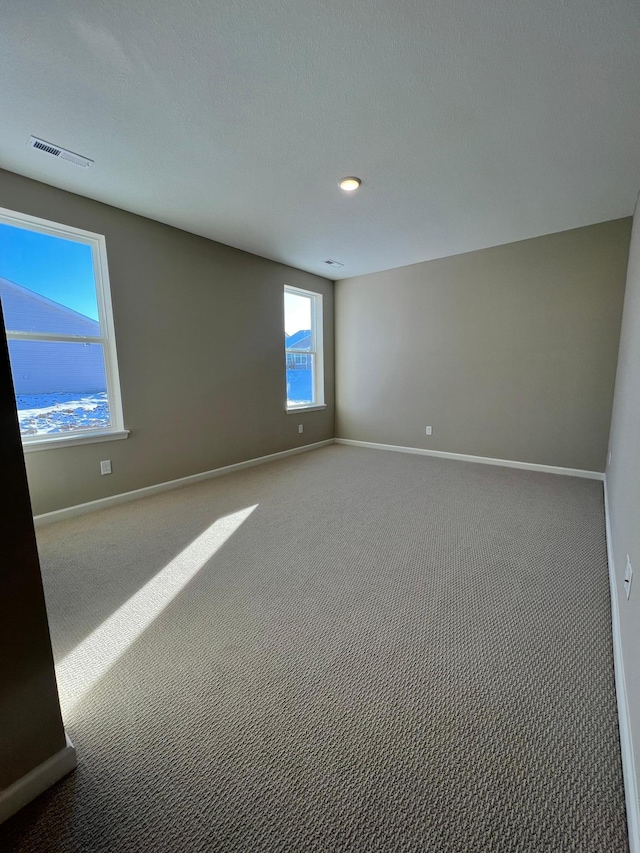 carpeted spare room featuring visible vents and baseboards