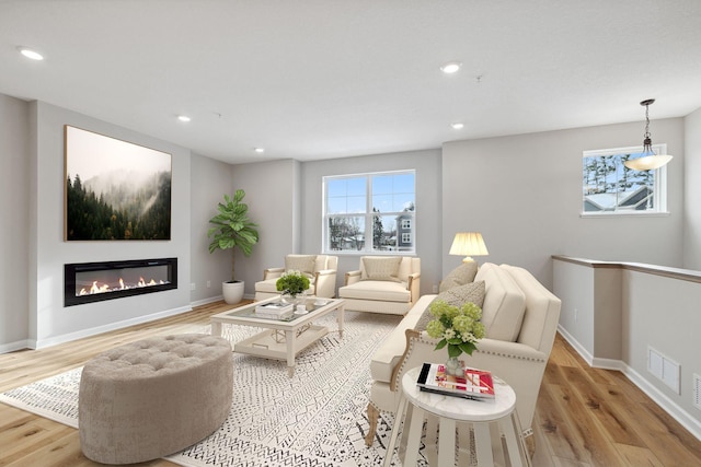 living area featuring light wood-style flooring, recessed lighting, and baseboards