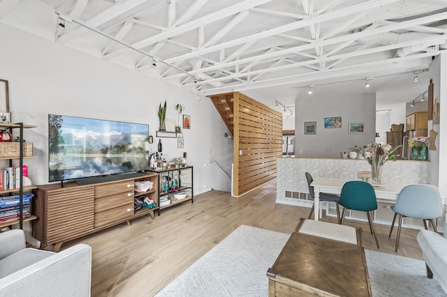 living room featuring rail lighting, stairs, visible vents, and wood finished floors