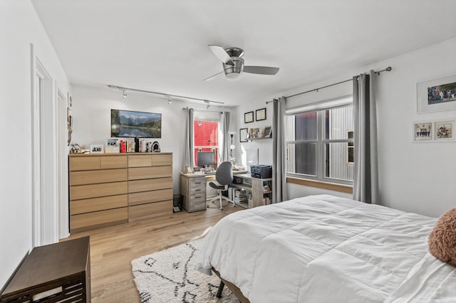 bedroom with ceiling fan, wood finished floors, and track lighting