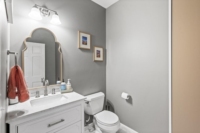 bathroom featuring baseboards, toilet, and vanity