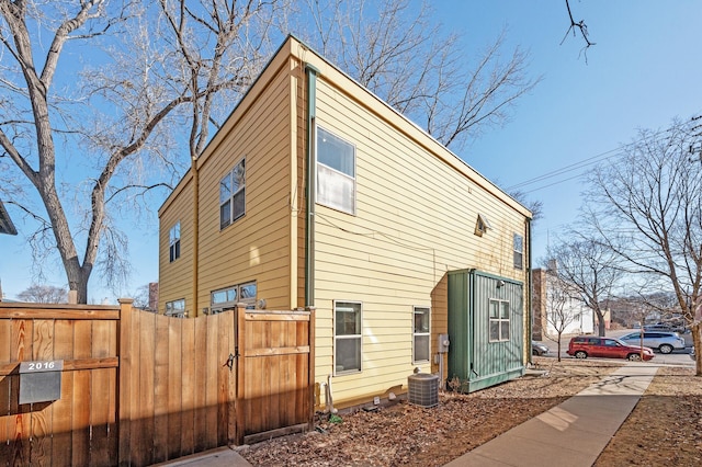 view of side of property featuring central air condition unit and fence